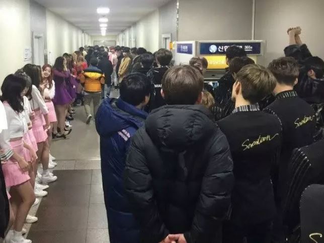 Kpop idol groups wait in line to greet music show producers.